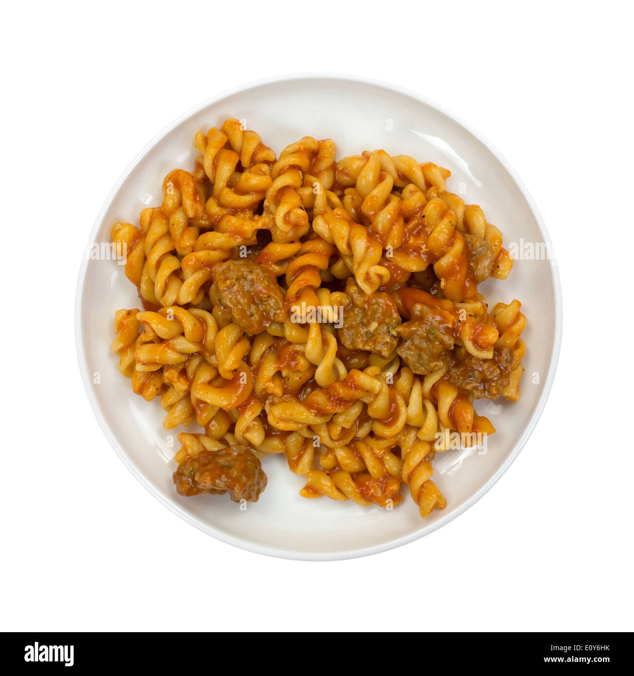 Top view of a serving of spiral pasta in a tomato sauce with small chunks of Italian sausage on a small plate. Stock Photo
