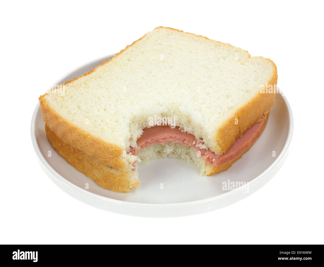A bitten baloney sandwich with white bread on a small plate Stock Photo