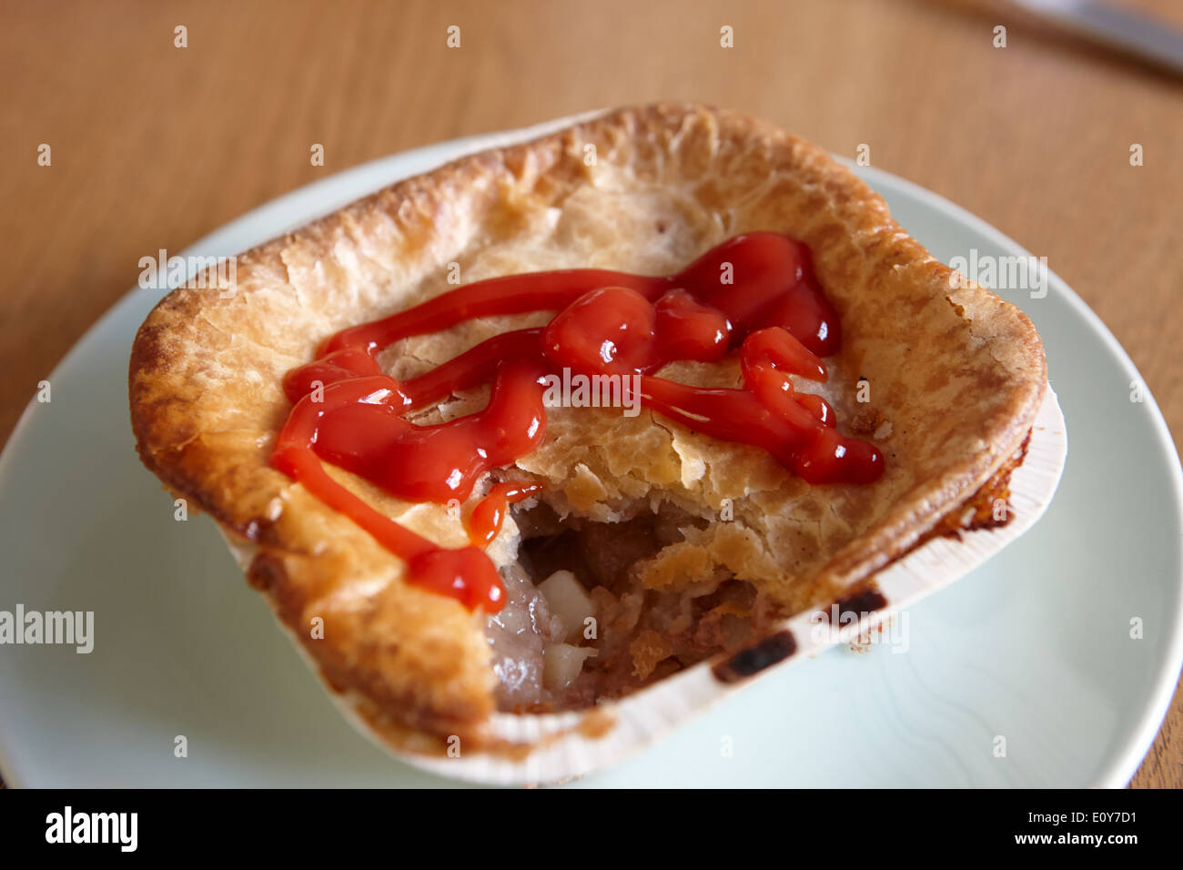 baked scouse pie in carton covered in tomato sauce Stock Photo