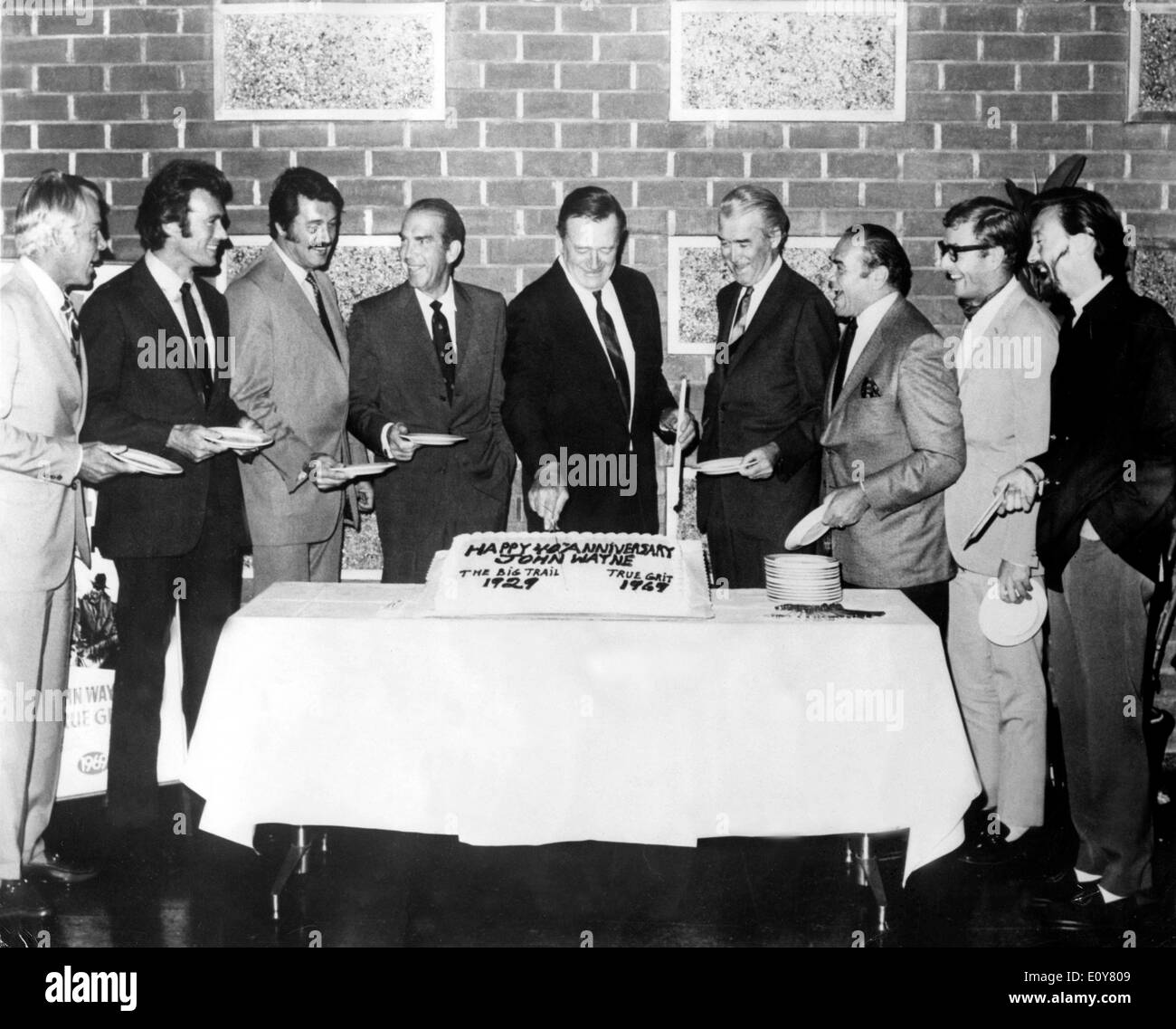 Actor John Wayne cuts his cake surrounded by friends Stock Photo