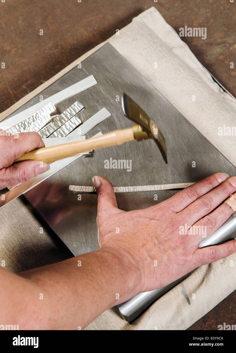 Artisans Nicole & Harry Hansen, Sterling & Steel, create original sterling silver and iron pieces. Close-up of hand and tool Stock Photo