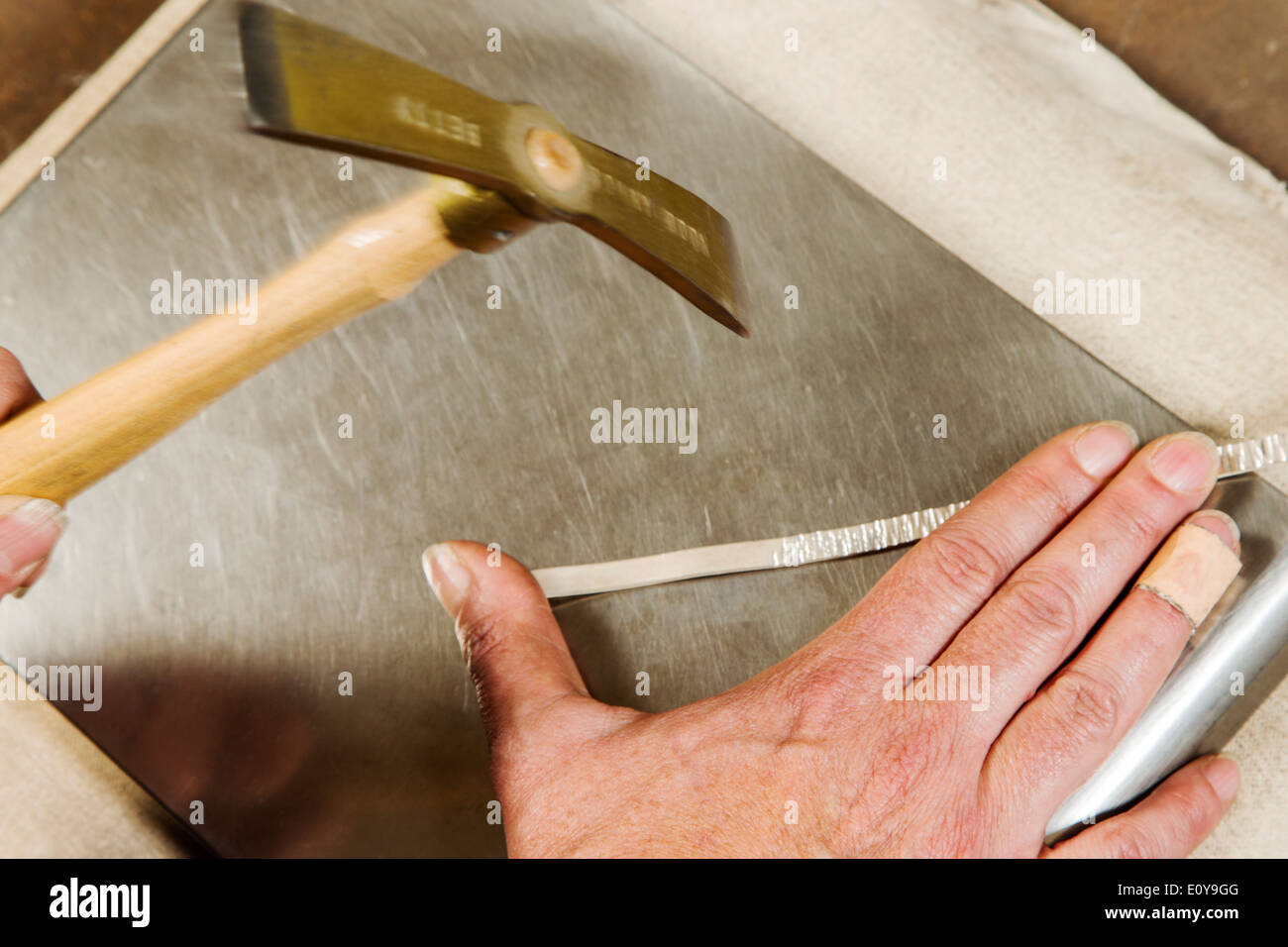 Artisans Nicole & Harry Hansen, Sterling & Steel, create original sterling silver and iron pieces. Close-up of hand and tool Stock Photo