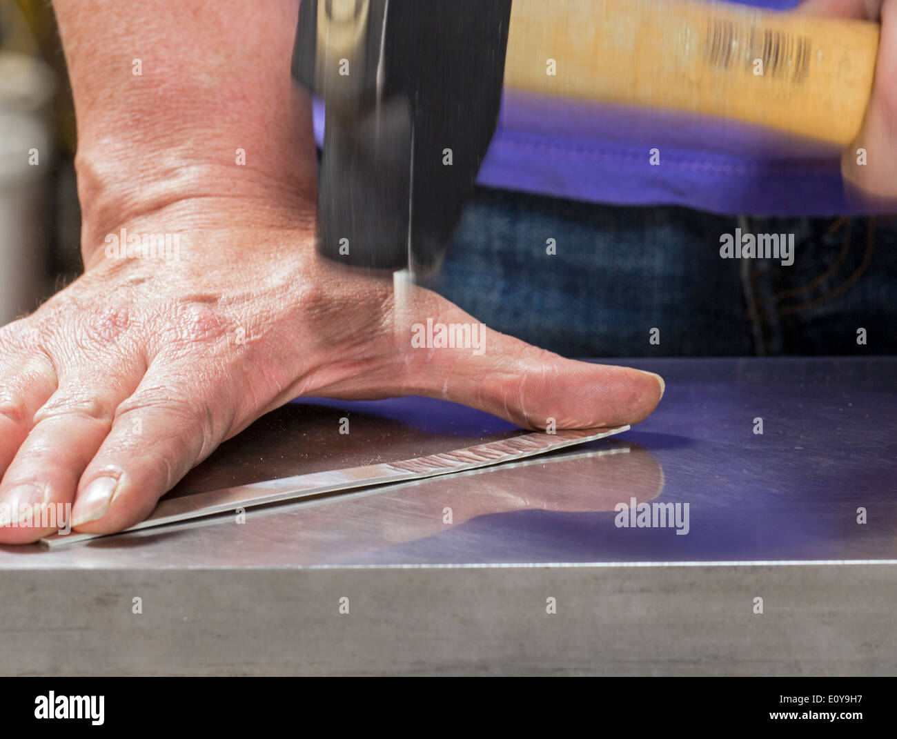 Artisans Nicole & Harry Hansen, Sterling & Steel, create original sterling silver and iron pieces. Close-up of hand and tool Stock Photo