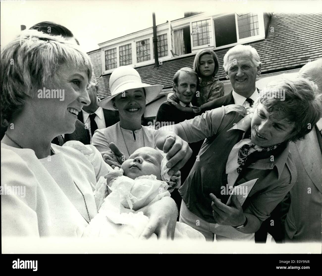 Jun. 06, 1969 - Tommy Steele's Daughter Christened Tommy Steele's daughter, Emma Elizabeth, was christened today at a private ceremony in the garden of their home, Teddington. The ceremony was performed by Father John Bebb, who officiated at Today's wedding. Photo Shows: Tommy wipes his daughter's head with cotton wool after the christening ceremony. Emma Elizabeth is held in the arms of his godmother, Polly James, who appeared with Tommy in ''Half a sixpence'' in New York. Stock Photo