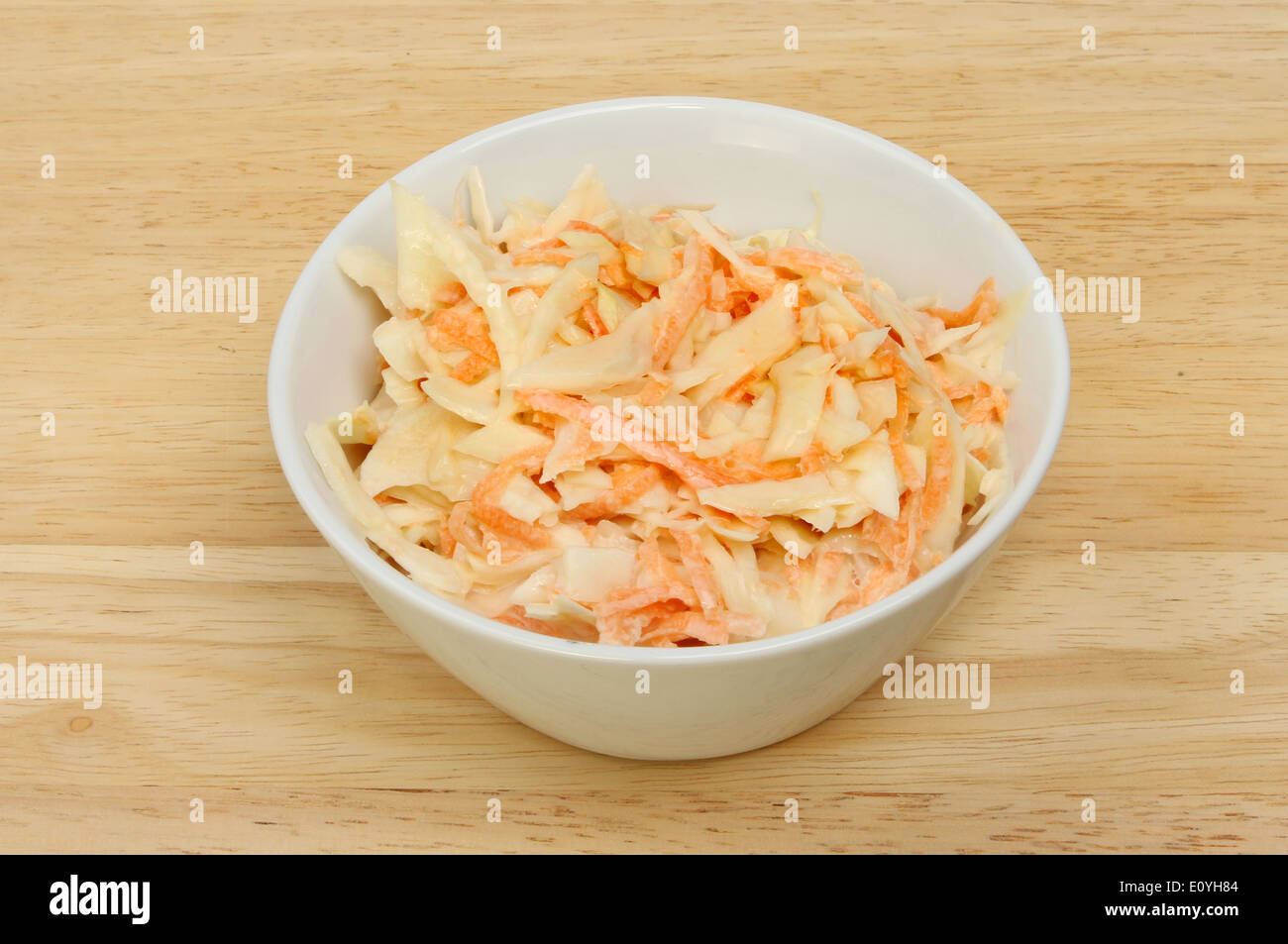 Coleslaw salad in a white bowl on a wooden board Stock Photo