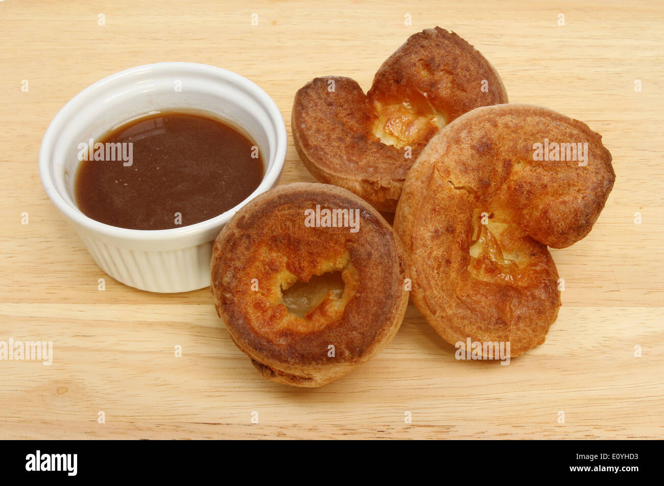 Yorkshire puddings with gravy in a ramekin on a wooden board Stock Photo