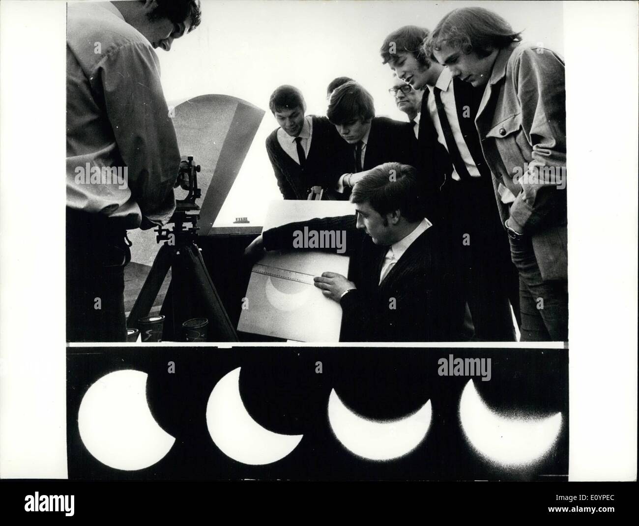 Feb. 02, 1971 - Partial eclipse of the sun: Weather on Tower Hill provided near perfect conditions for viewing yesterday morning's two-hour partial eclipse of the sun. Only part of the final phase of the eclipse was obscured by cloud. The shadow reached its maximum at 10.41 a.m. Three sunspots were visible during the early as black patches. Photo shows top picture: Christopher Laycock, 23, watched by other students as he measured yesterday's partial eclipse of the sun on an image projected through a Theodolyte with a mirror at the Merchant Navy College, Tower Hill Stock Photo