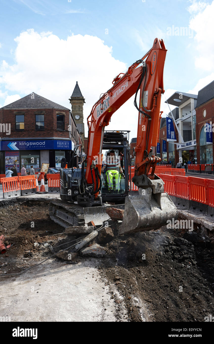 man operating hitachi excavator digging up city streets Preston Lancashire UK Stock Photo