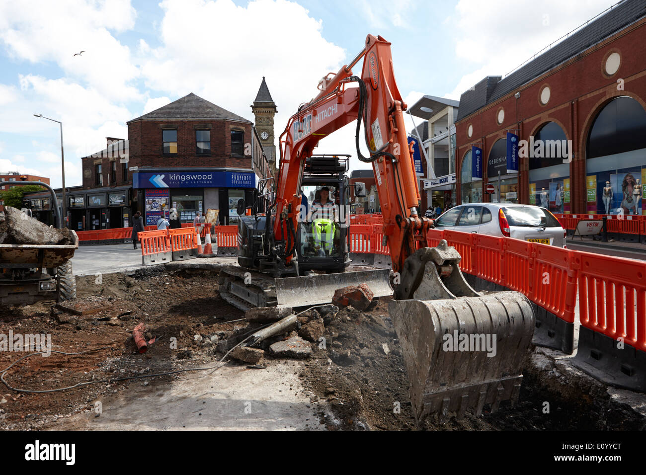 man operating hitachi excavator digging up city streets Preston Lancashire UK Stock Photo