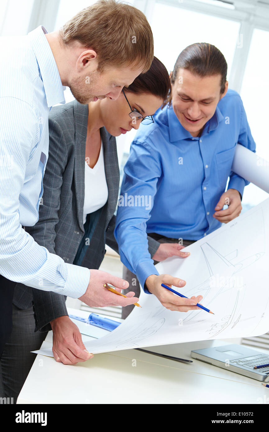 Three engineers examining a sketch of plane Stock Photo
