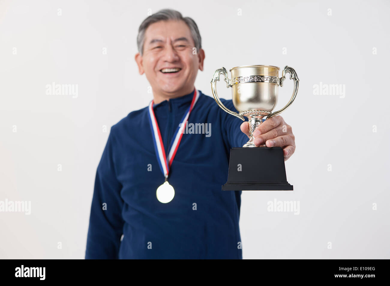 an old man posing with a medal and a trophy Stock Photo