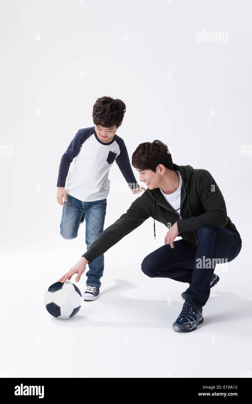 a father and a son playing with a football Stock Photo
