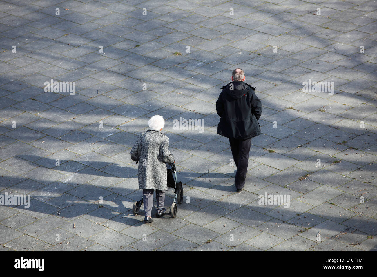 people, seniority, physical handicap, old-timer woman walking with a wheeled walker, man as carer Stock Photo