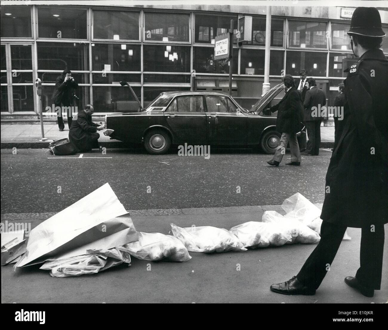 Mar. 03, 1973 - Gelignite found in car at Scotland yard: A bomb containing about 150 lb of gelignite was found in car opposite Scotland Yard today. The car, which had false number plates, was parked in Broadway outside the Post Office. The bomb was defused and the road blocked. Photo shows a police constable stands guard over the sacks of gelignite found inside the car while Scotland Yard men continue to search the car seen in the background outside Scotland Yard today. Stock Photo