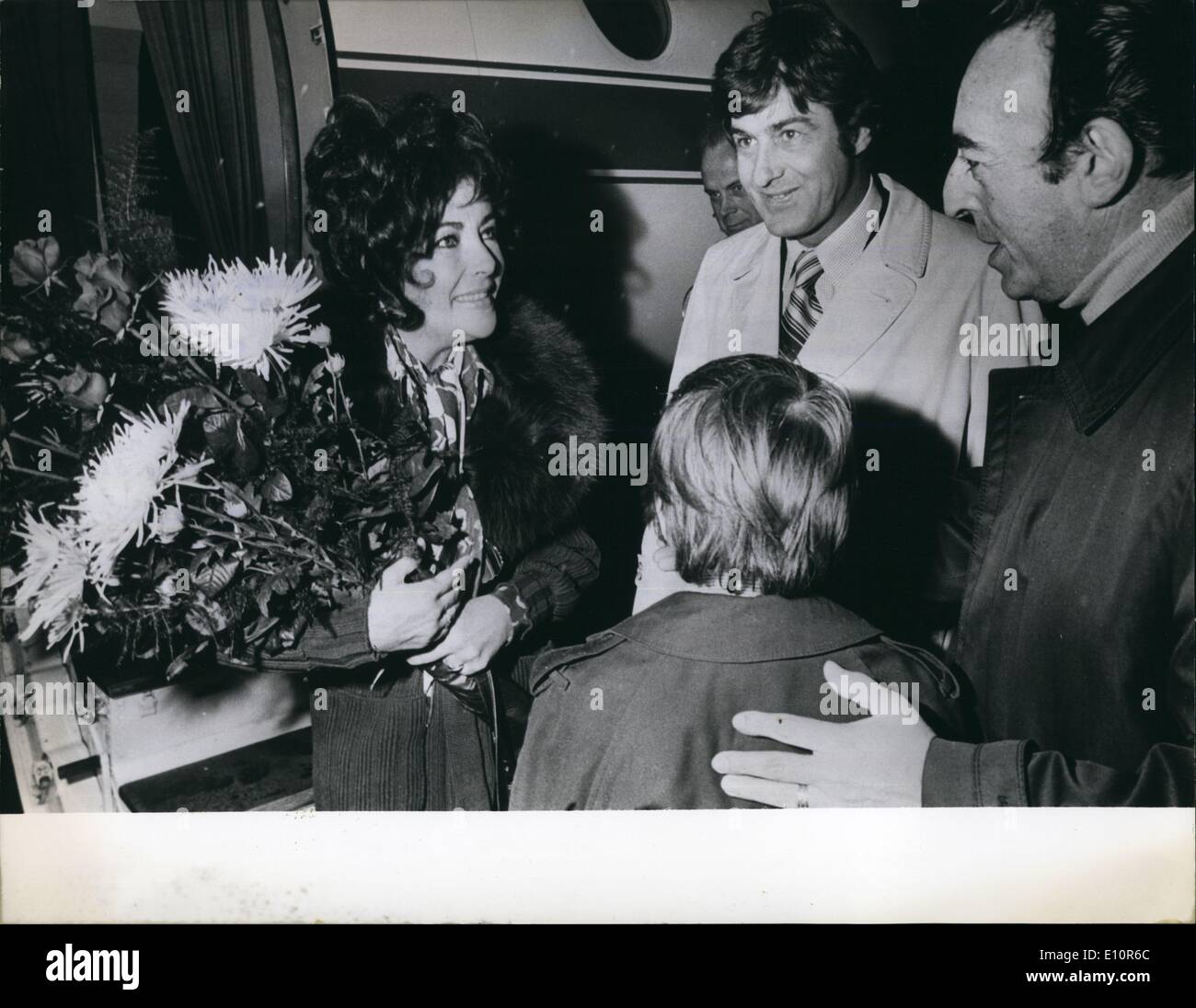 Oct. 10, 1973 - Film star Liz Taylor arrived at Hamburg airport for finishing her new film ''Identikit'' in this city: The American actress, dressed in a green jersey punt-suit with broad black fur collar was abord a French Mystere which belongs to producer Mr. Rizzoli. A limping Miss Taylor was supported by Mr .Henry Wyngard, her Dutch boyfriend, for during the previous shooting of the film she has opened to hurt her leg. Press Chief Allan Buckhantz and his son Neil, 9, were expecting, the American actress, the latter handed a bouquet of red roses and white chrysanthemums to her Stock Photo