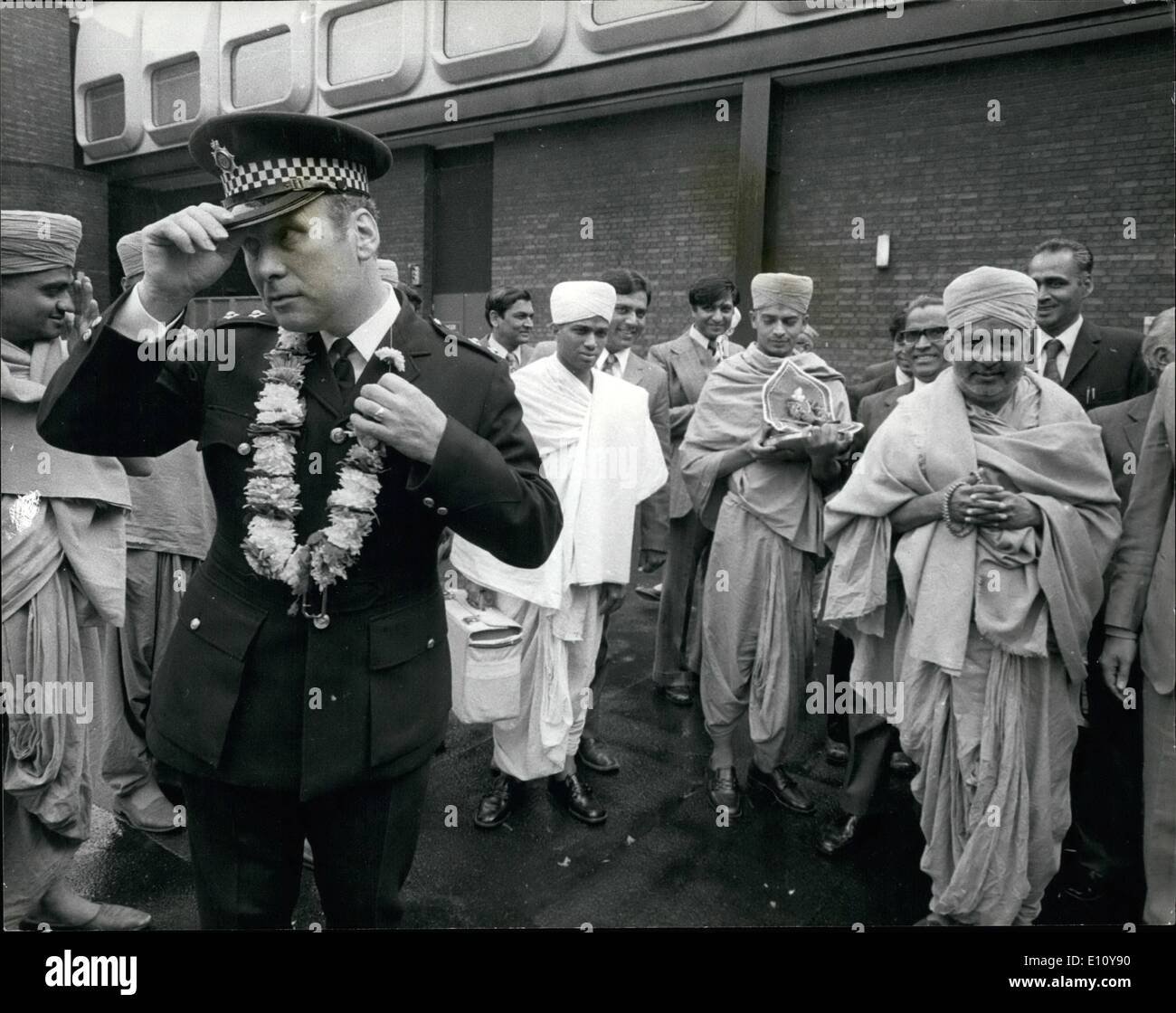 Jun. 06, 1974 - Policeman's Resistance Overcome by Hindu Flower Power - Police Inspector Rawlinson Walks away after accepting the offer of a garland, which he had at first declined, from His Divine Holiness Shree Swami Shastri Narayansarupdasji, Spiritual head of the Shree Swaminarayan Hindu Mission, where he arrived at heathrow Airport on Saturday, Seen on right. Stock Photo