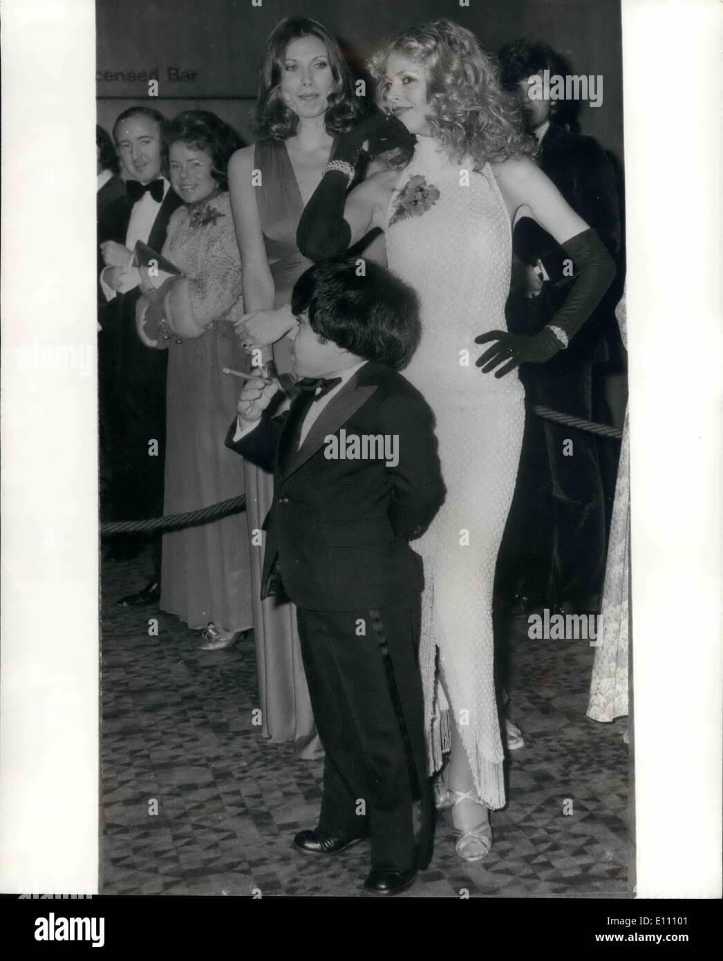 Dec. 12, 1974 - Little Man You Have A Busy Night: The cigar-smoking French actor Herve Villechaize and lovely actresses, Britt Ekland (right) and Maud Adams, who appear in the latest James Bond film ''The Man With The Golden Gun'', wait in the foyer of the Odeon Theatre, Leicester Square, for last night's arrival of the Duke of Edinburgh to attend the premiere of the film, which aids the Stars' Organisation for Spastics, The national Playing Fields Association and the Variety Club of Great Britain. Stock Photo