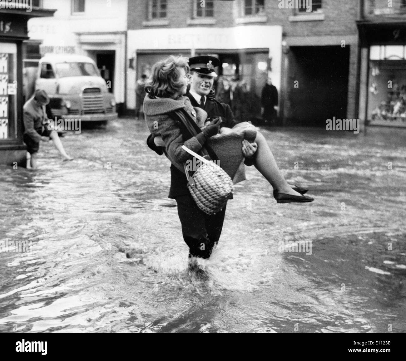 Officer carries woman through flood water Stock Photo