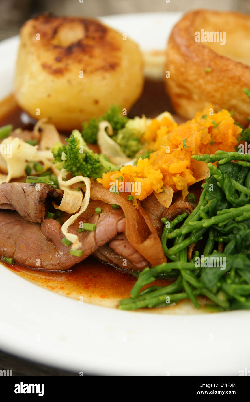 Roast beef dinner with roast potatoes, Yorkshire pudding and vegetables mashed swede and samphire Stock Photo