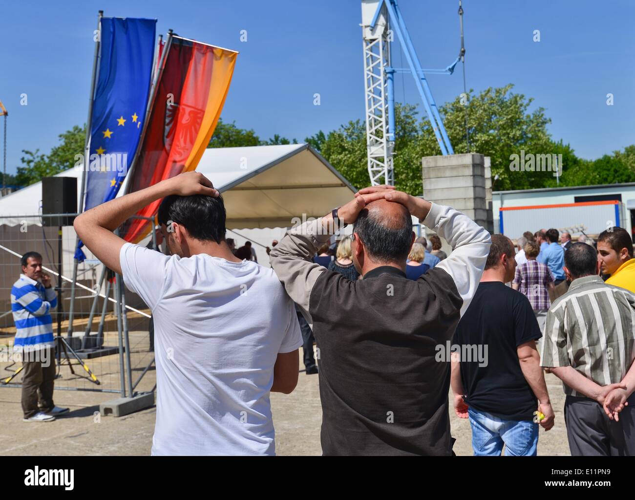 Eisenhuettenstadt, Germany. 21st May, 2014. Asylum seekers attend the cornerstone laying ceremony for the new family home at the first contact asylum seekers' facility in Eisenhuettenstadt, Germany, 21 May 2014. The old building is in bad condition and the rooms are too small. The 6, 4 million euro building project sponsored by the interior and finance ministry should be finished by the end of 2015 and offer places to 237 refugees. Photo: PATRICK PLEUL/dpa/Alamy Live News Stock Photo