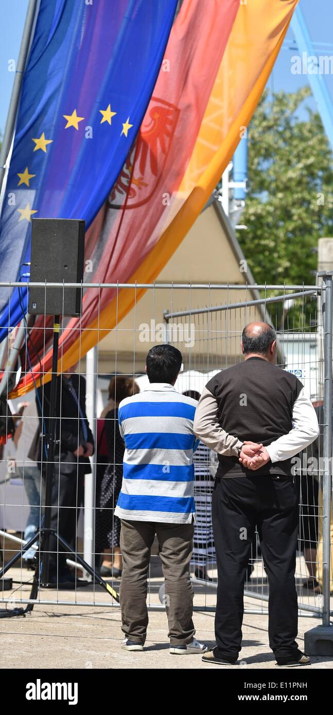 Eisenhuettenstadt, Germany. 21st May, 2014. Asylum seekers attend the cornerstone laying ceremony for the new family home at the first contact asylum seekers' facility in Eisenhuettenstadt, Germany, 21 May 2014. The old building is in bad condition and the rooms are too small. The 6, 4 million euro building project sponsored by the interior and finance ministry should be finished by the end of 2015 and offer places to 237 refugees. Photo: PATRICK PLEUL/dpa/Alamy Live News Stock Photo