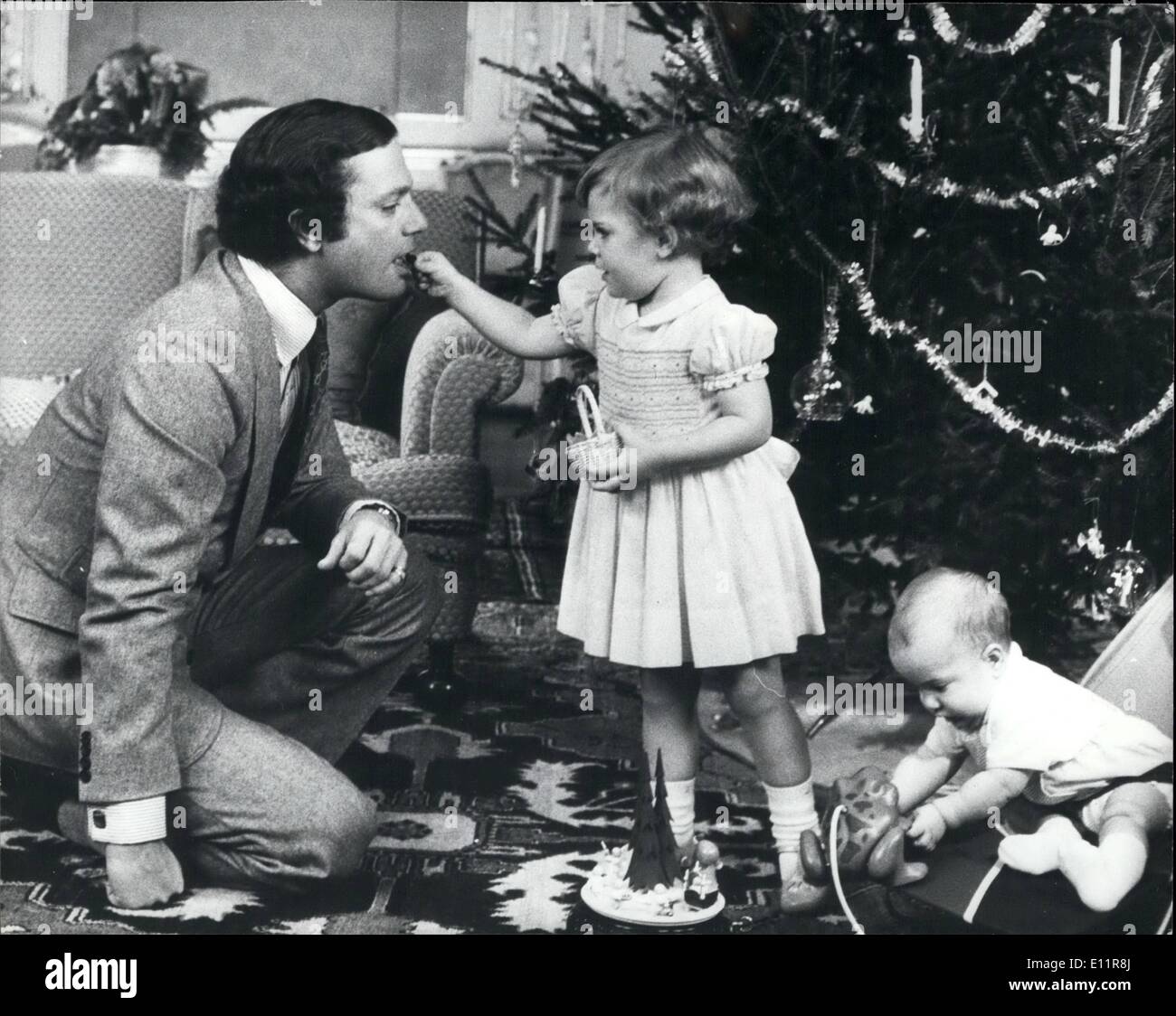 Dec. 12, 1979 - Crown Prince until Christmas: Prince Carl Philips's first Christmas. He will be heir to the throne until the end of the year when a change in the constitution will make his elder sister, Princess Victoria aged 2 1/2 year old heir. Photo shows Princess Victoria aged 2 1/2, gives her father King Carl Gustof a sweet, while her brother Prince Carl Philip plays with a toy, during the dressing the Christmas tree at Stenhammar Castle. Stock Photo