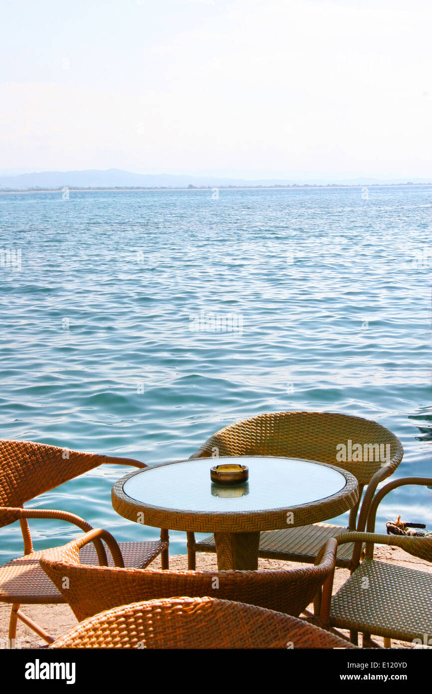 Cafe table by the ocean, on a beautiful calm sunny day in Katakolon, Greece. Stock Photo
