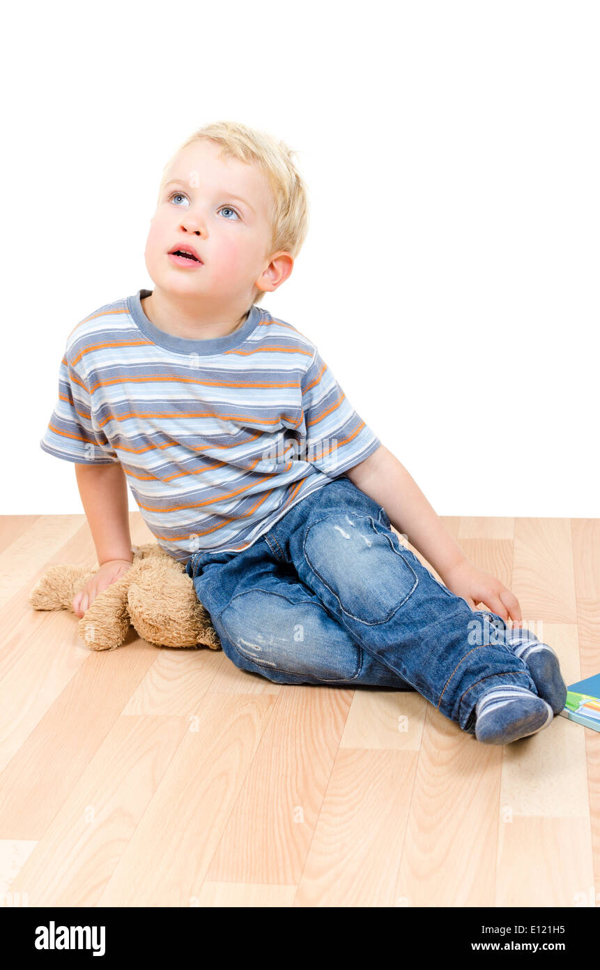 Cute little blond boy sitting with his teddy bear and a book isolated ...