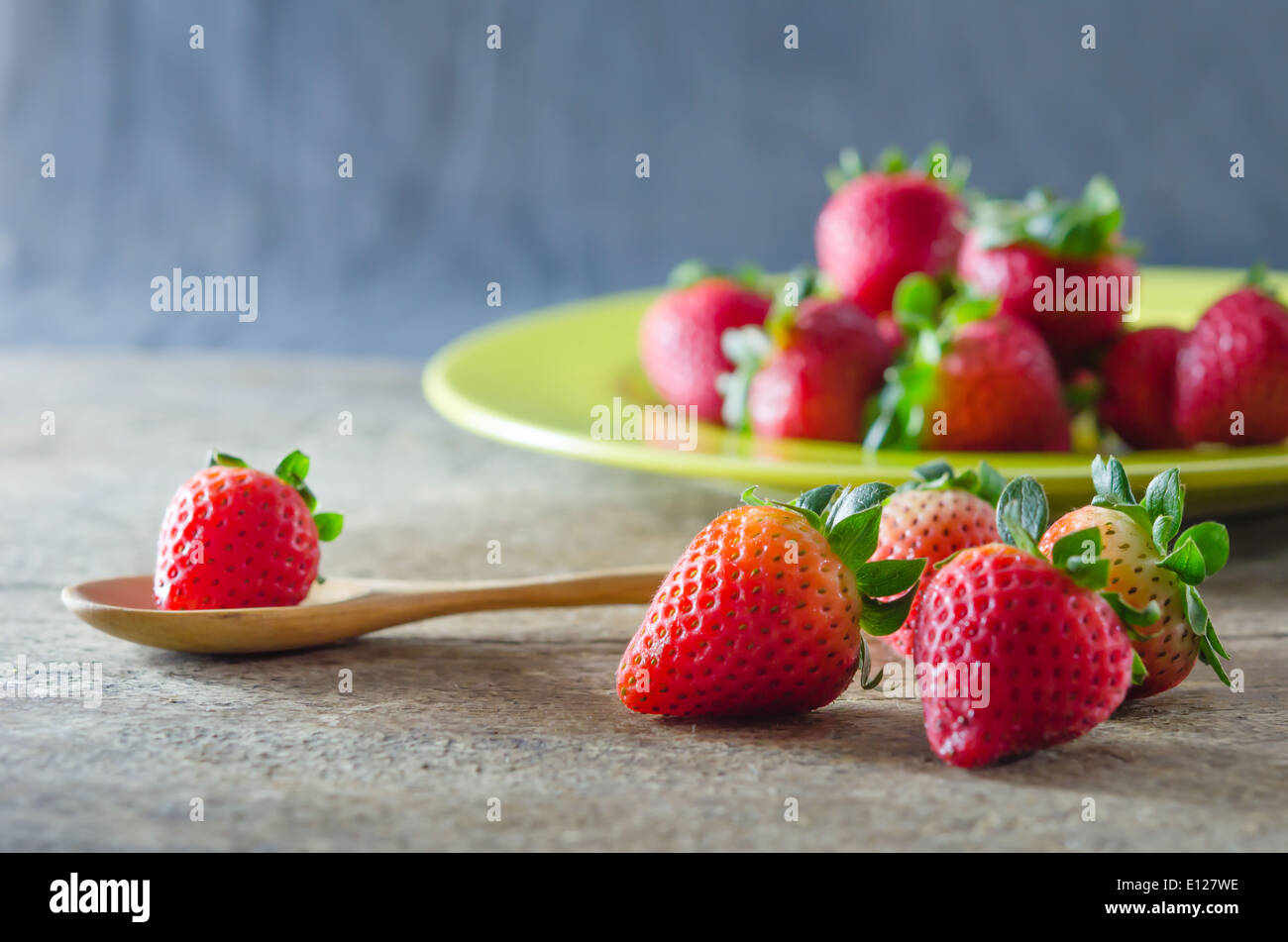 still life of fresh red strawberries on dish over wooden background ...