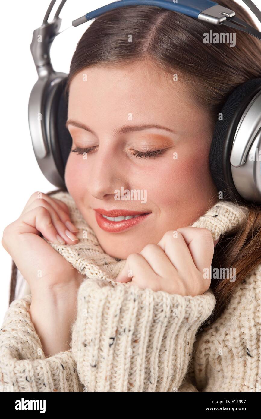 Oct. 29, 2009 - Oct. 29, 2009 - Portrait of happy woman enjoying music with headphones wearing turtleneck on white background C Stock Photo