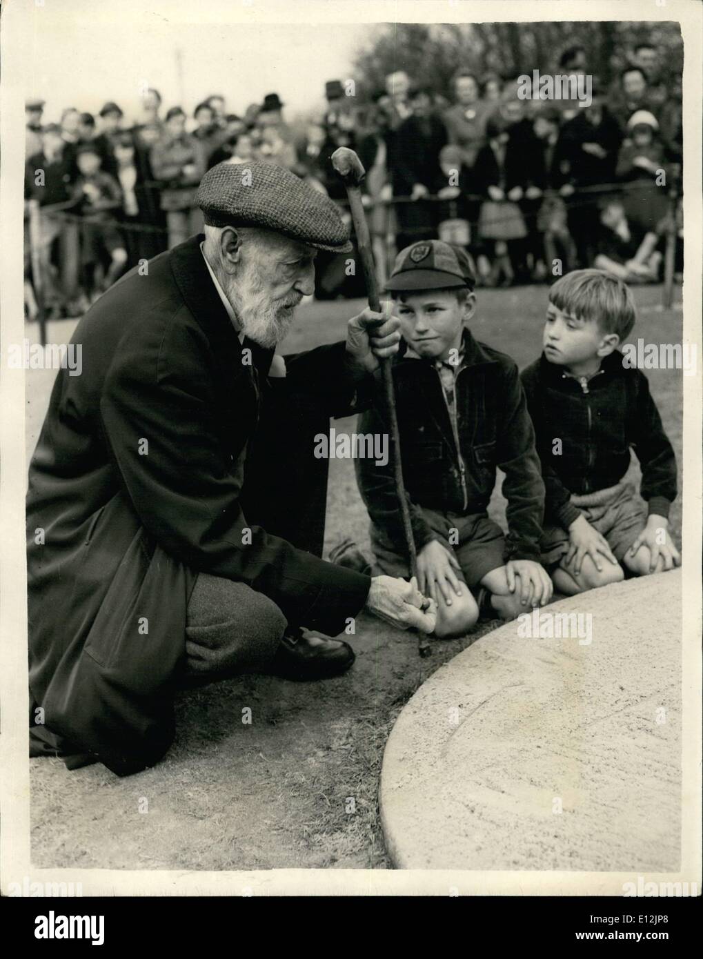 Feb. 24, 2012 - Annual Marbles Championship in Surrey ''Pop'' Maynard And The Youngsters: The annual Good Friday Marbles Championship was held today at Tinsley Green, Surrey. Photo shows George ''Pop:'' Maynard the 84 year old Captain of the ''Copthorne Spitfires'' - in play watched by two youngsters brothers Richard (10) and Frank (7) Goodedge - at Tinsley Green this morning. Stock Photo