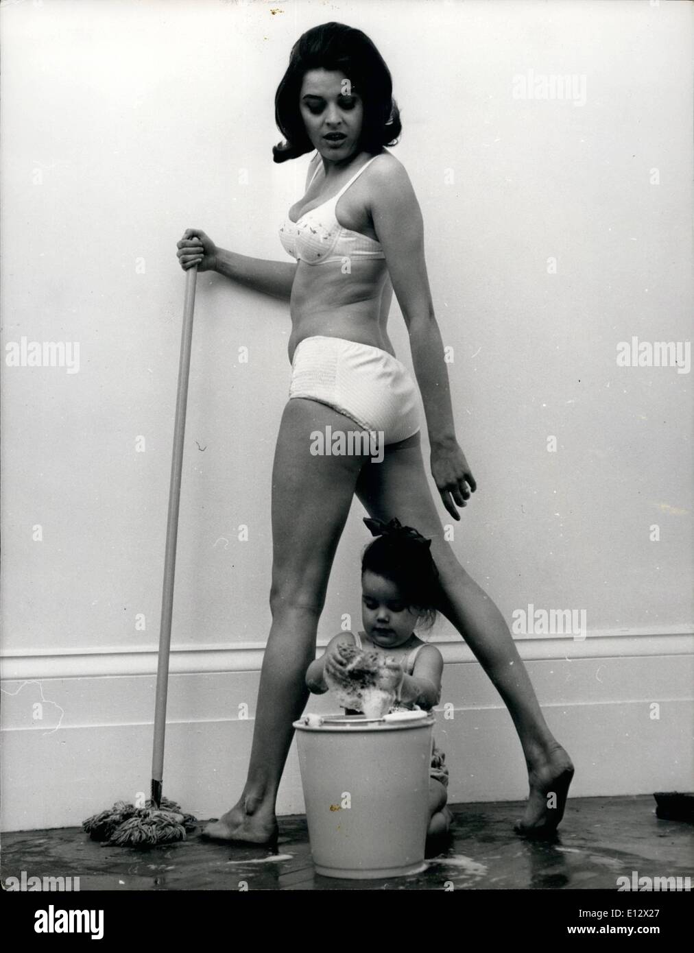 Feb. 26, 2012 - Cleaning Up With The New Queen Of Satire: As the time near for the BBC's new satire show which will replace ''Not so Much...'' Lynda Baron, who is Eleanor Bron's successor is making the most of her little spare time by cleaning up in her new London flat. On this task Lynda, red-headed and twenty five, is helped by her daughter Sarah aged 2 1/2. Being a realist, Lynda resses properly for the job in hand - and what more suitable attine for a Summer day's scrubbing, than a bikini, and especially when you have a figure like Lynda's and a daughter who likes to help make a splash Stock Photo