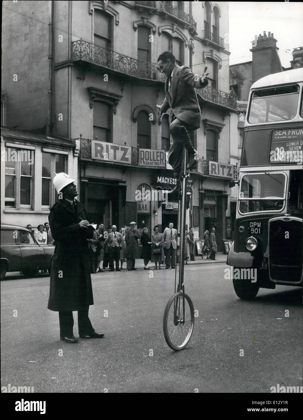 Feb. 26, 2012 - Banner Forbutt's job is always in the balance; Riding a one wheel cycle needs a nice sense of balance, keeping himself eight feet off the ground, up a slender shaft mounted on a single wheel, is a constant source of amusement to those who see Brighton's ice circus, and to local citizen who are now getting used to seeing him make his way to and from the theater on his strange vehicle. The local police wave his on just as if he was any other cyclist, and don't be surprised if you ride on the top deck of a bus and he leans over the side and asks you for a light Stock Photo