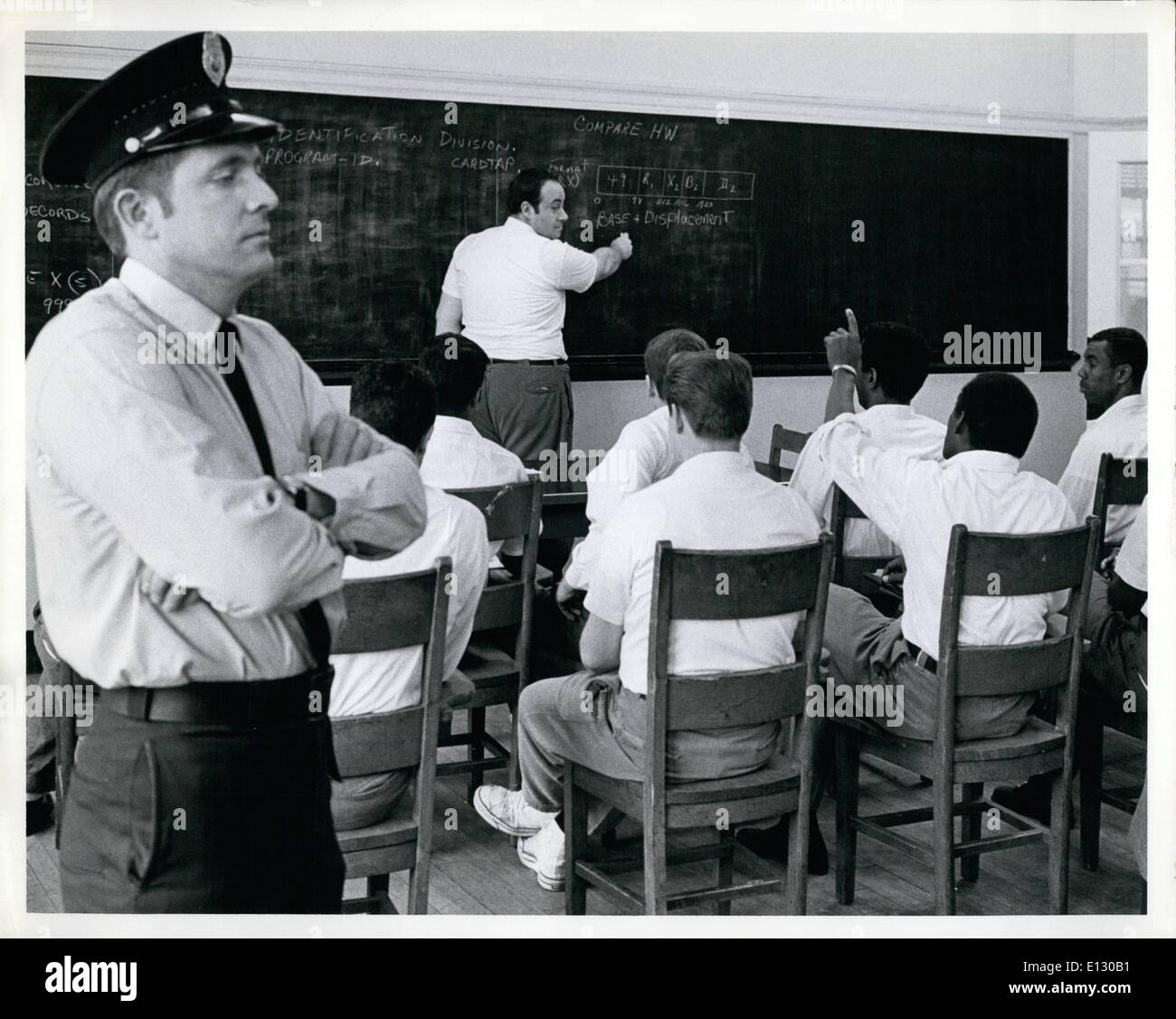 Feb. 26, 2012 - Sing Sing convicts trained in Computer skills: Correction Officer Joseph D. Cassidy, Left, stands guard as convict Bernie W., at blackboard reviews computer problems with other students before graduation exercises this Friday, March 28, 1969. Bernie W. will be valedictorian at these exercises. Stock Photo