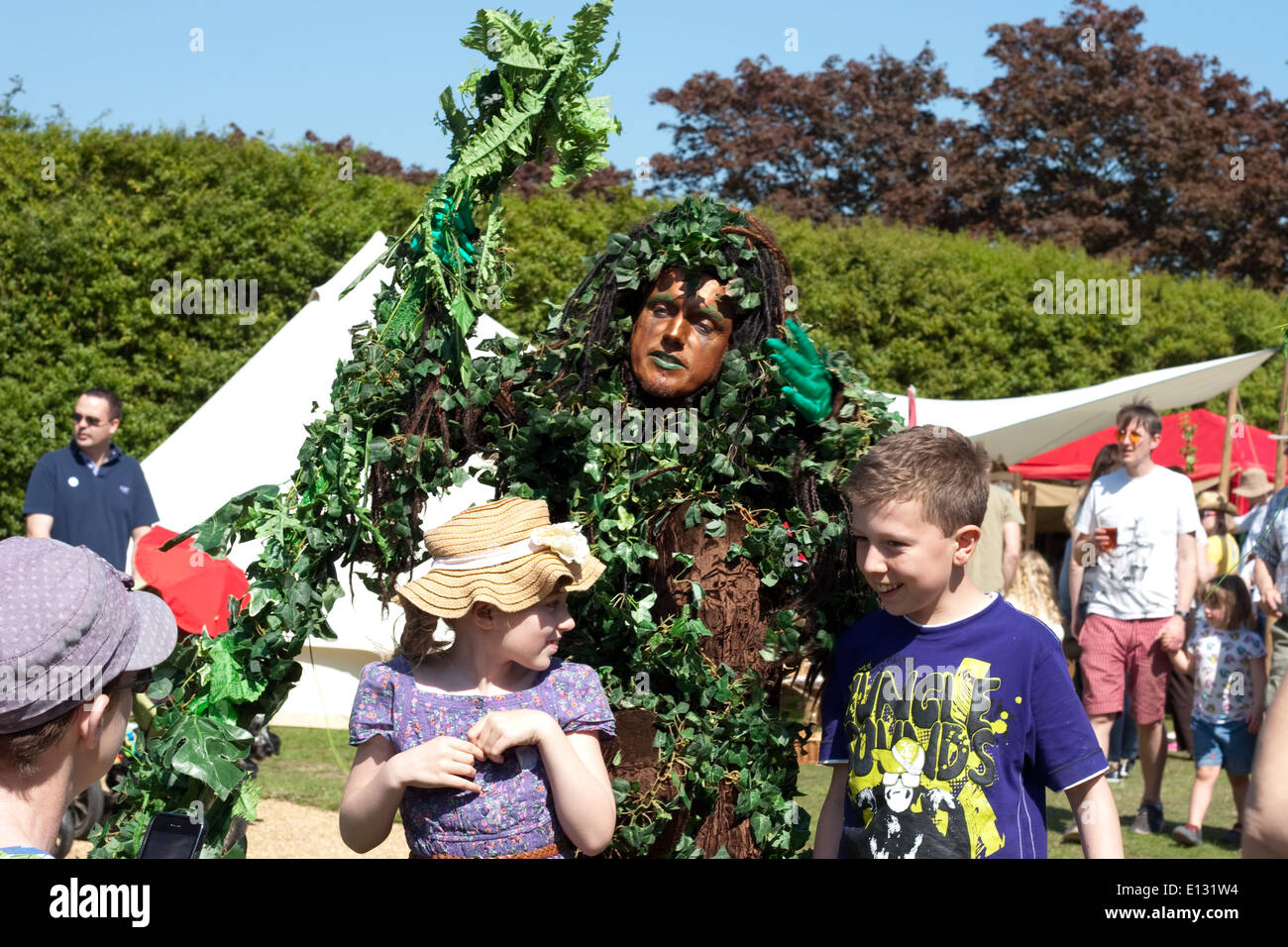 Man dressed as a tree interacts with happy young children Stock Photo