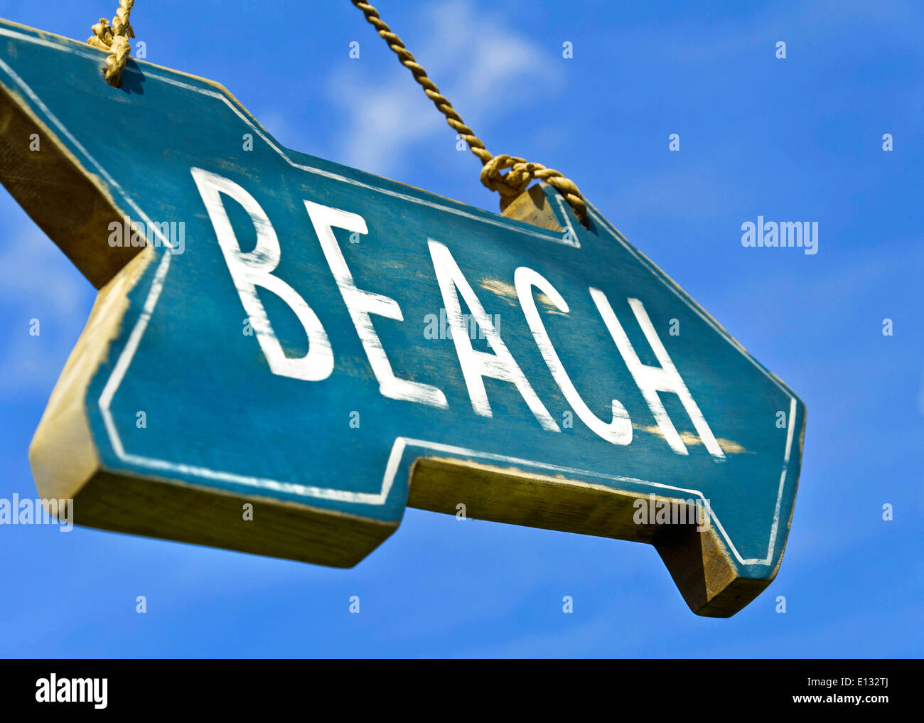 Low angle view of rustic weathered 'Beach' sign against blue sky summer holiday vacation concept Stock Photo