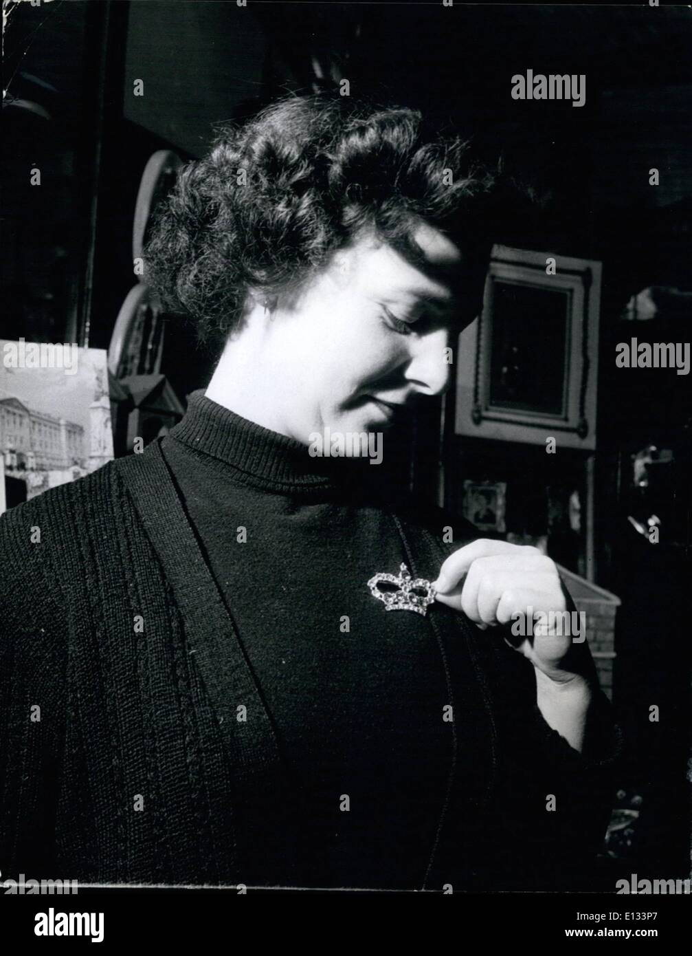 Feb. 26, 2012 - In a souvenir shop in Trafalgar Square, Miss Joyce Powell tries on a paste brooch in the shape of a Crown, one of the popular souvenirs for Coronation year. Coronation Souvenirs For Overseas Visitors: Just as soon as the date of the Coronation was announced manufacturers started to make souvenirs and now Gift and Souve air shops in London and other large cities are already doing a brisk trade, especially with overseas visitors, who, although they will not be in England for next year's Coronation, want to take souvenirs back home with them Stock Photo