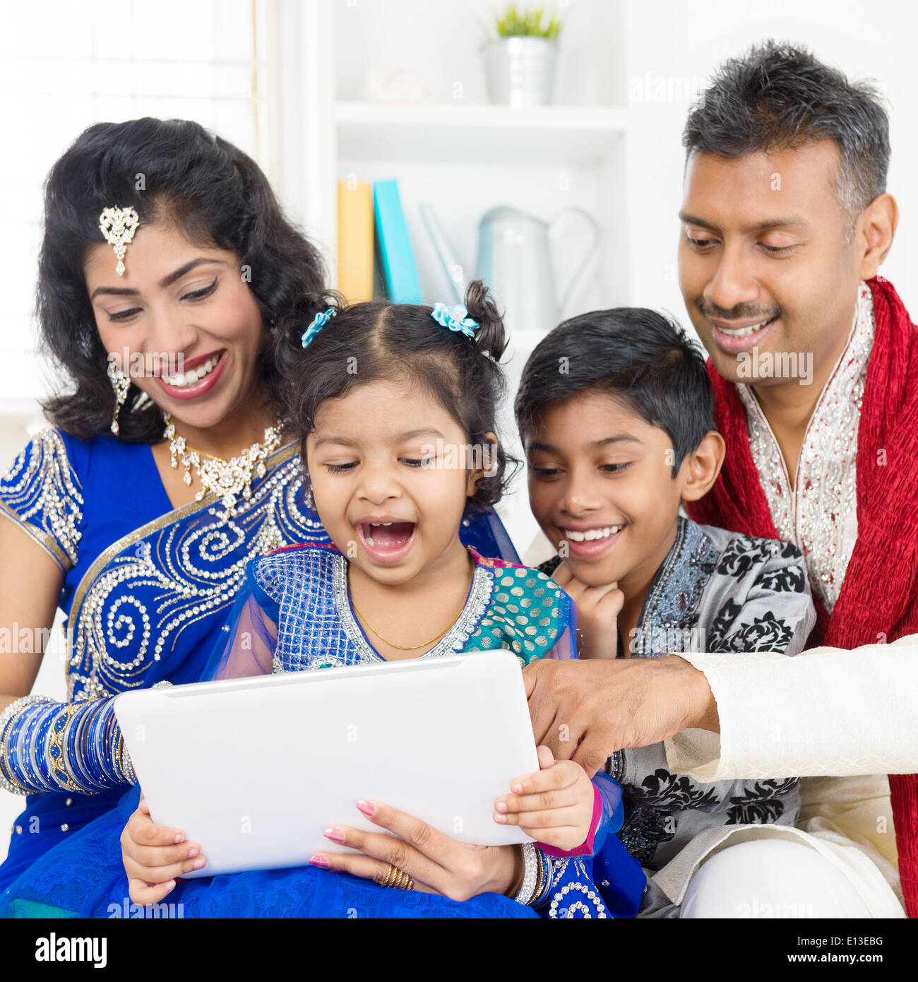 Indian family using digital computer tablet at home. Asian family ...