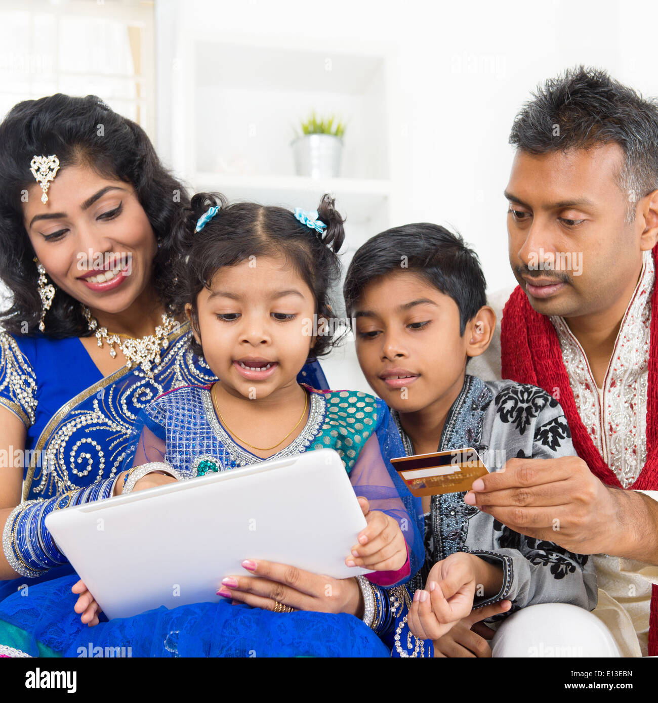 Indian Asian family using digital tablet pc computer online shopping with  credit card at home. India family living lifestyle. Happy smiling parents  and children Stock Photo - Alamy