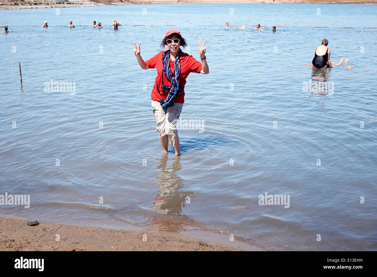 Asian woman making the V sign standing in the Dead Sea, Israel Stock Photo