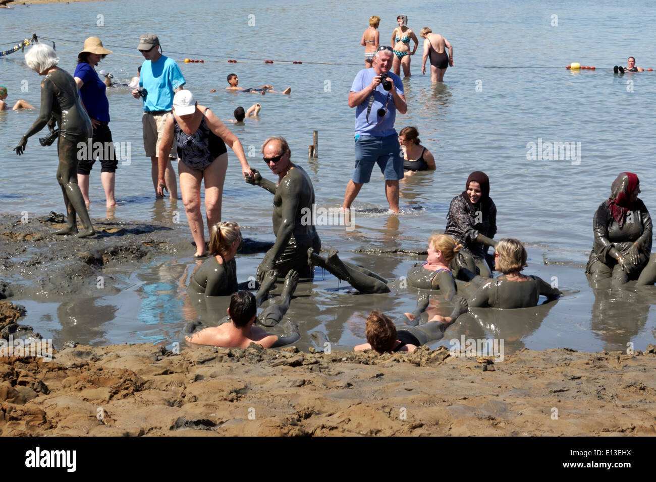 People bathing in the mud in the Dead Sea, Israel Stock Photo