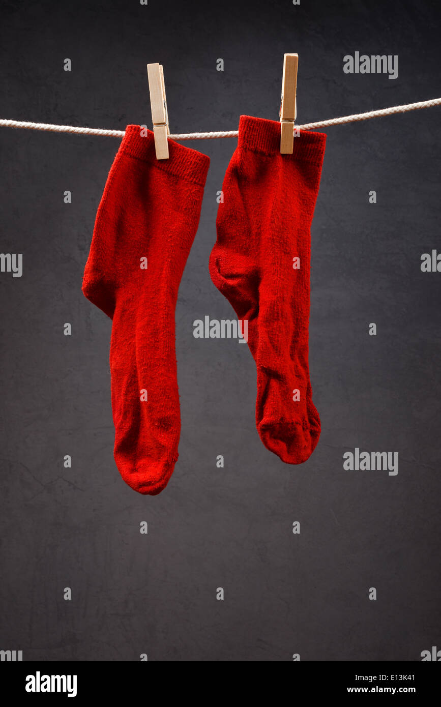 Old red socks hanging on rope attached with clothespins to dry
