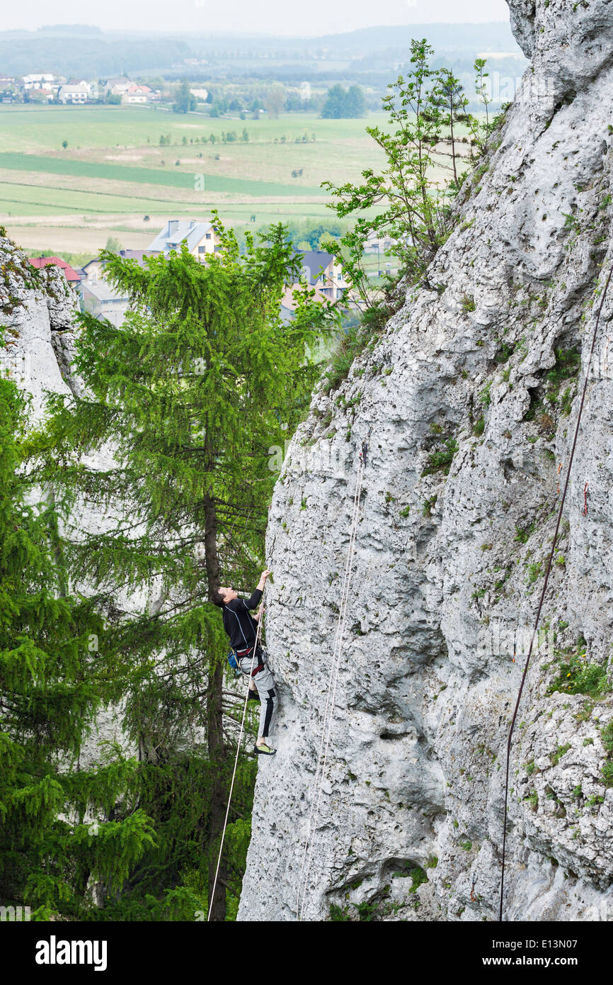 Man climbing steep and high rocky wall. Stock Photo