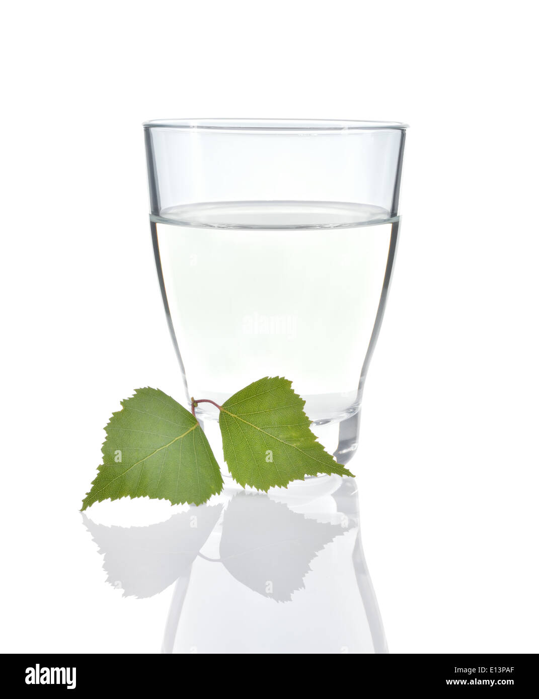 Birch sap in a glass and birch leaves isolated on white background