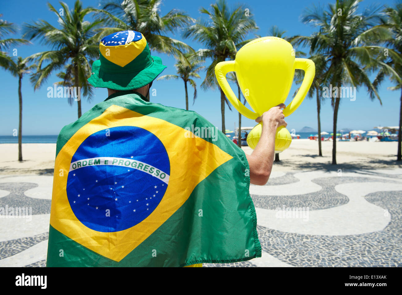 Proud Brazilian in flag regalia holding inflatable trophy at Copacabana Beach Rio de Janeiro Brazil Stock Photo