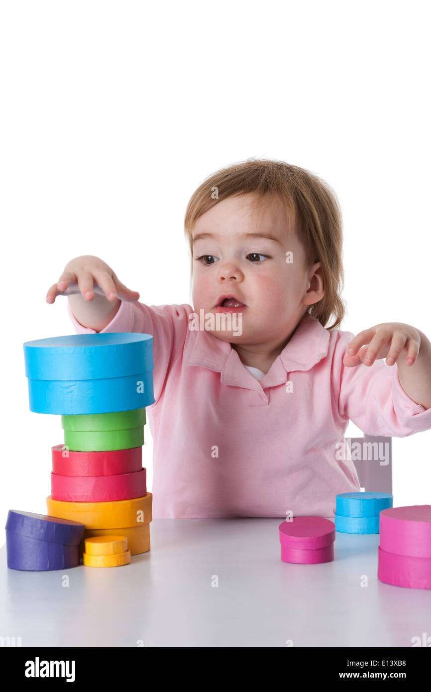 Little girl playing with colored boxes on white background Stock Photo ...