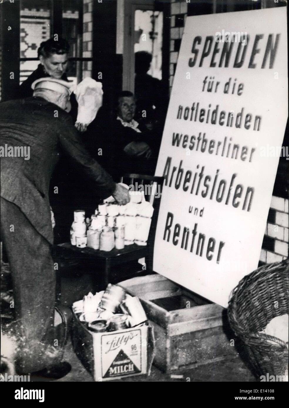 Mar. 31, 2012 - A deeply moving picture!.: The inhabitants of the East-secctor of Berlin and of the Soviet zone are forced on some stations of Berlin to deliver the food-stuffs they have got in Western Berlin. And the propaganda-poster informs that the delivered rations will be distributed to West-Berlin jobles persons, The seized food-stuffs are piled up high in the collection points. Our picture was taken on Potsdam Station shows an inhabitant of the Soviet zone who has just to lay down hi cans and food-stuffs before the propaganda-poster. Notice the disappointed face of the wife behind him Stock Photo