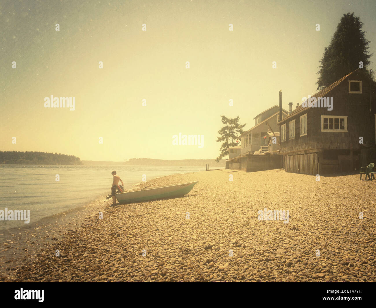 Caucasian man sitting in boat on rocky beach - Smartphone Captured Stock Image