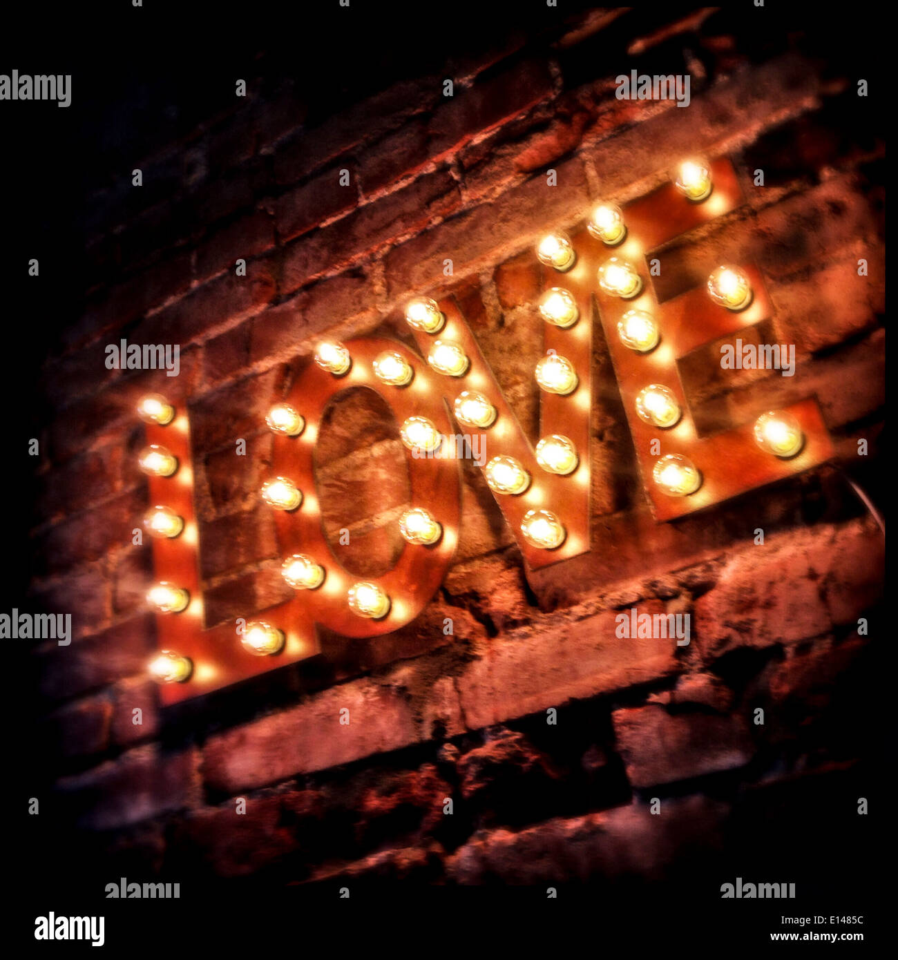 LOVE' sign lit up on brick wall - Smartphone Captured Stock Image