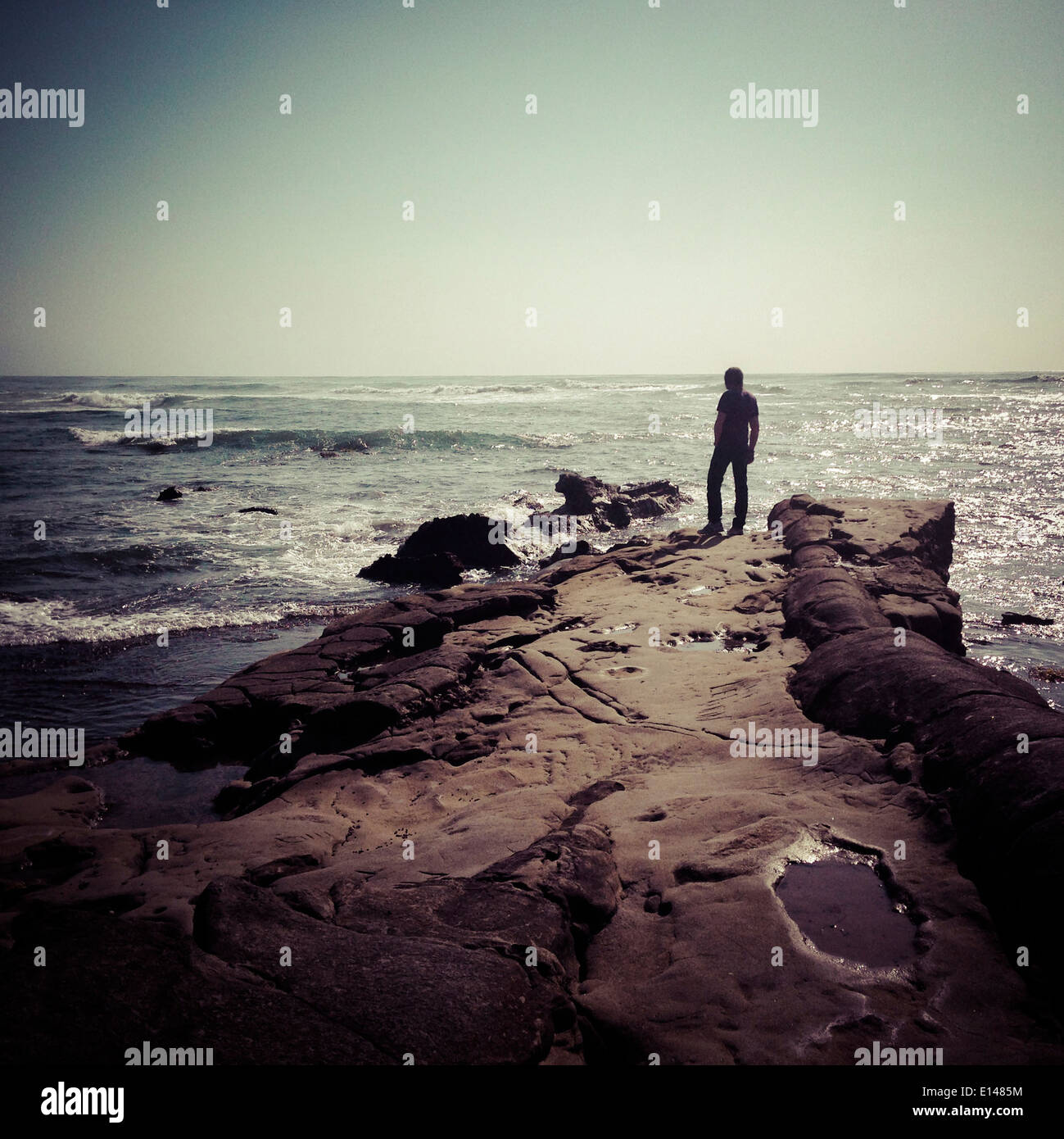 Man standing on craggy beach, San Diego, California, United States - Smartphone Captured Stock Image